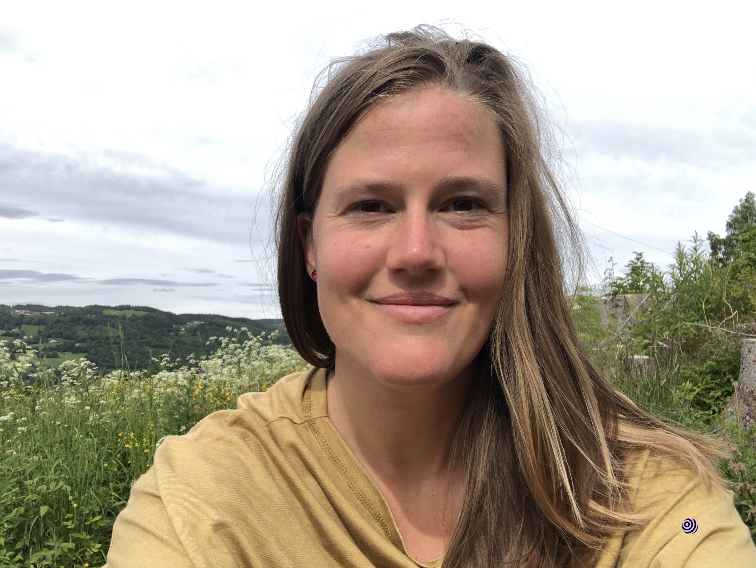 Me outside in nature, hillside flowers and tree stubs in the background